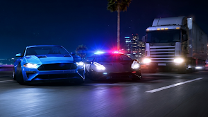 A blue muscle car fleeing a police cruiser past a truck at night