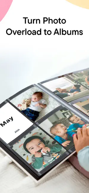 Printed photo album open to a May 2026 monthly card beside baby prints in pocket pages
