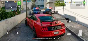 A red muscle car with a spoiler stopped by police cars on a walled street