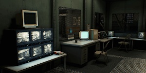 A guard station of CRT monitors and a desk beside a cell block door marked D-E