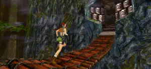 Lara dashing across a plank bridge in a torch-lit temple